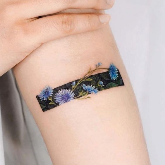 a woman's arm with blue flowers on it and a black band around the wrist