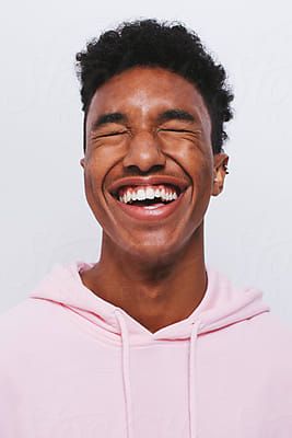 a young man smiling and wearing a pink hoodie