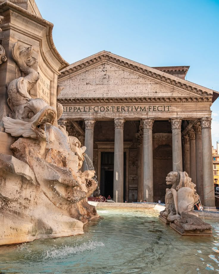 the fountain in front of an old building with statues on it's sides and columns