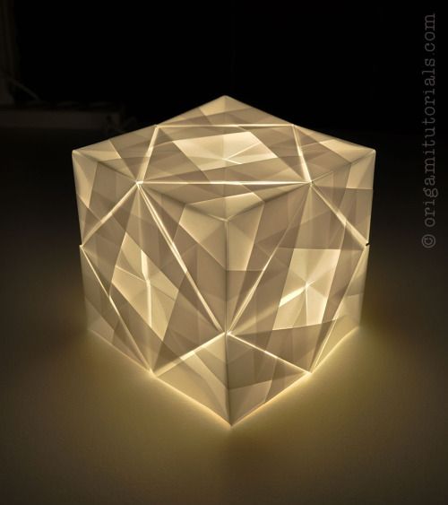 a white light that is on top of a black surface and it looks like an origami cube