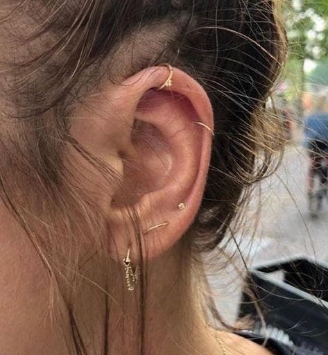 a close up of a person's ear wearing gold earrings