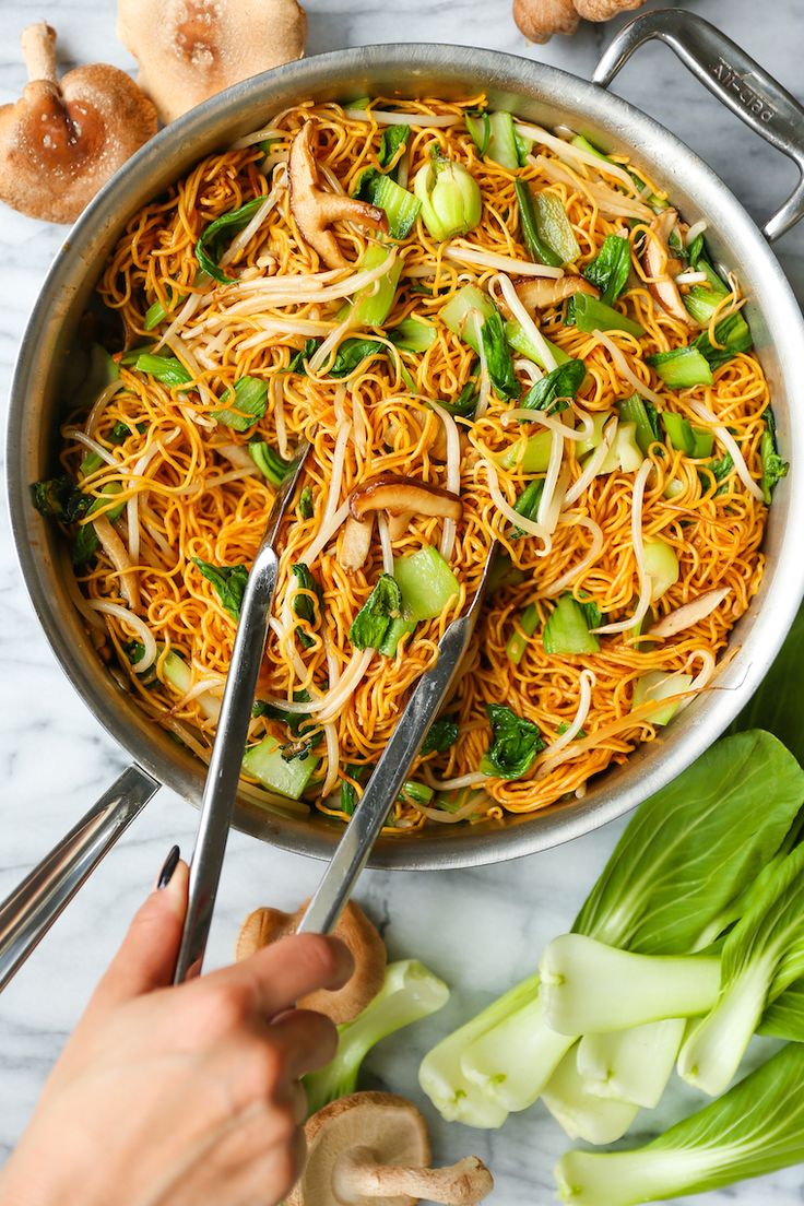 someone cutting up noodles in a pan with chopsticks next to it on a marble countertop