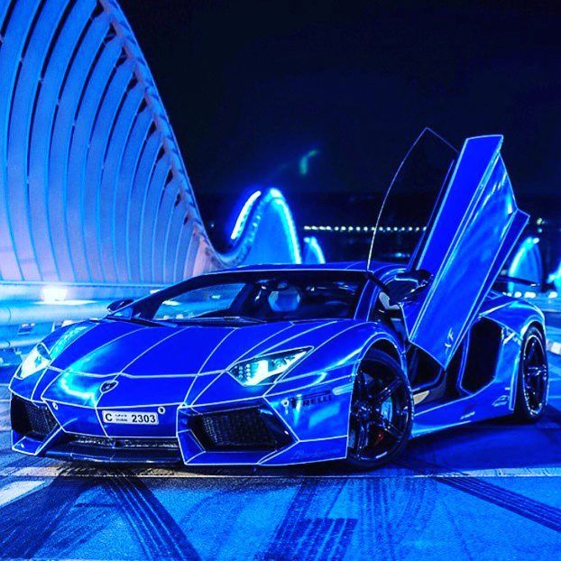 a blue sports car parked in front of a building at night with its doors open