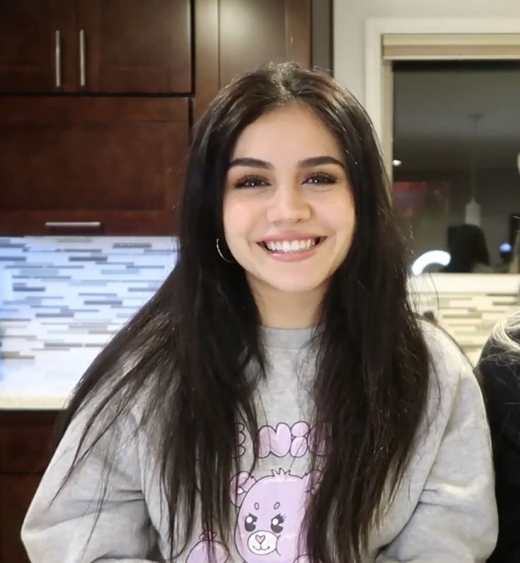 a girl with long hair is smiling at the camera while standing in front of a counter