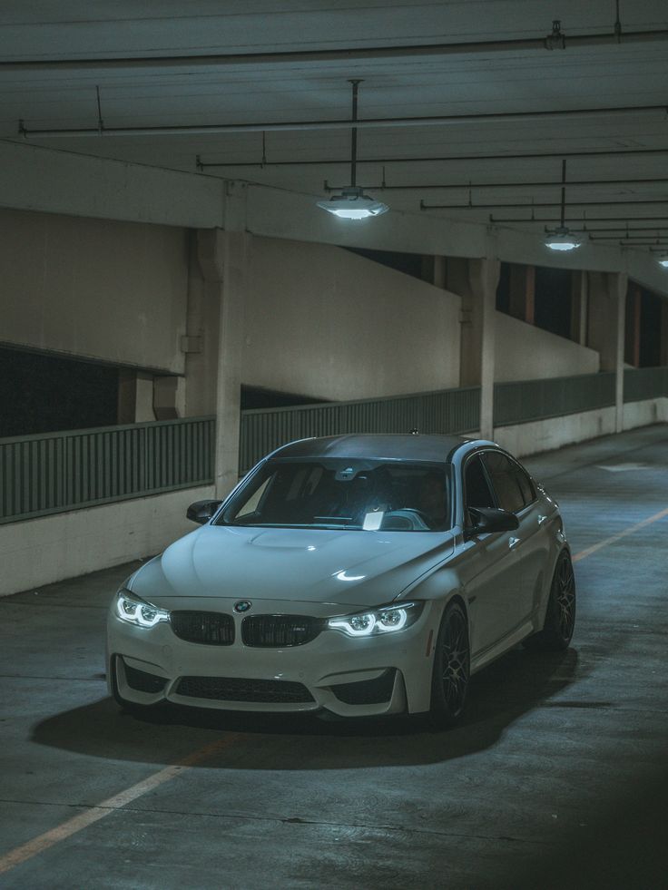 a white car is parked in an empty parking garage with no one around it at night