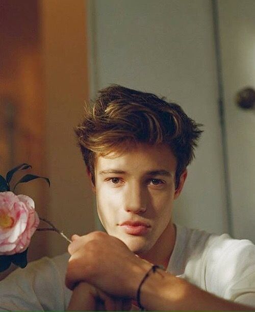 a young man is holding a flower in his hand