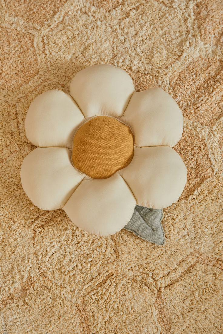 a white flower shaped pillow sitting on top of a bed