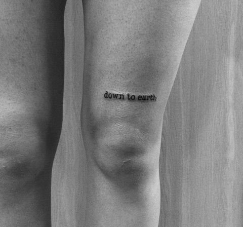 a black and white photo with the words down to earth tattooed on someone's leg