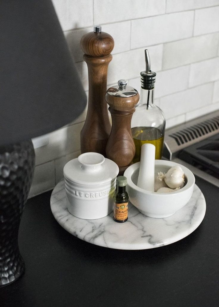 a marble plate with spices and condiments on it next to a black lamp