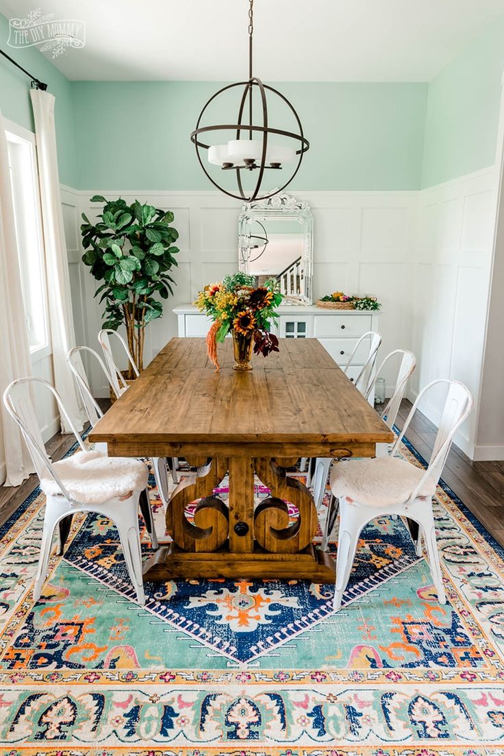 a dining room table with chairs and a rug on the floor in front of it