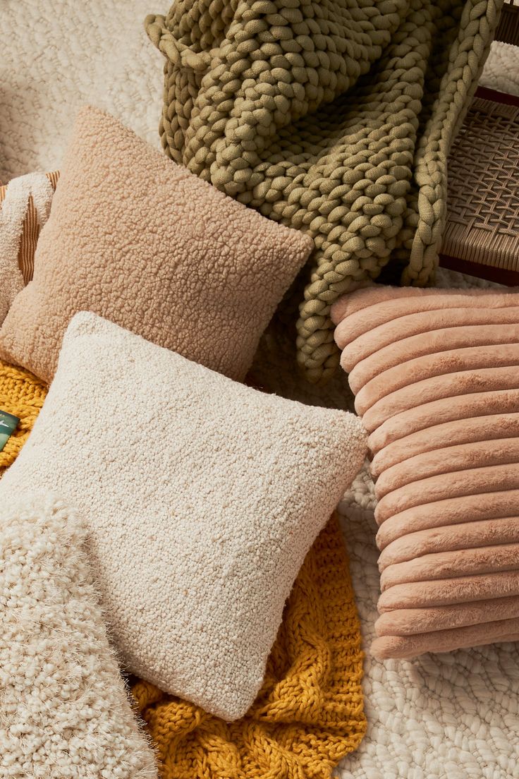 several pillows and blankets are laying on the floor next to each other, all different colors