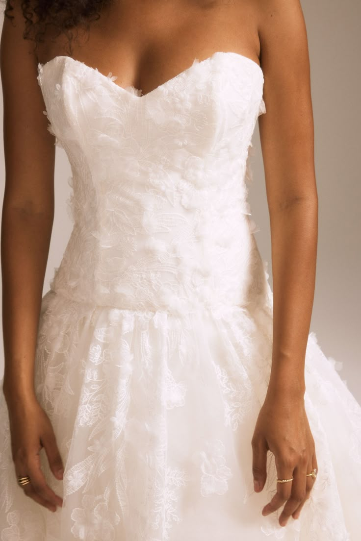 a woman in a white wedding dress posing for the camera with her hands on her hips