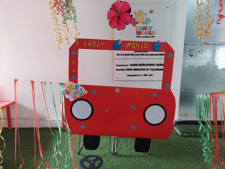 a red bus is sitting in the middle of some green carpeted area with streamers