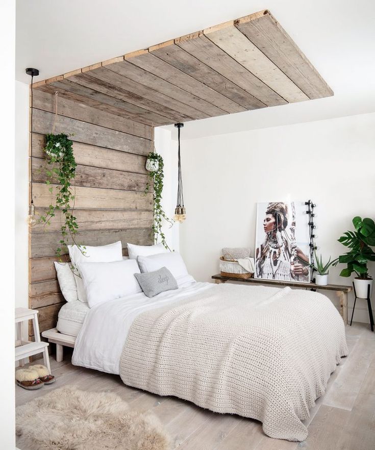 a bedroom with white walls and wood planks on the headboard, bedding is made