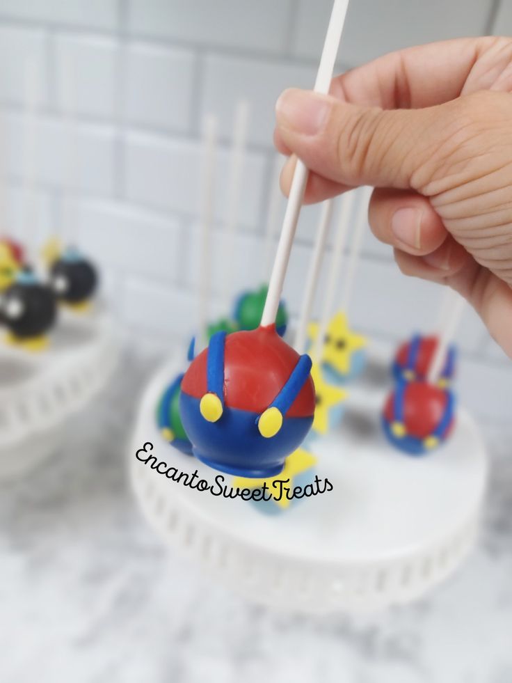 a hand holding a toothpick in front of a cake