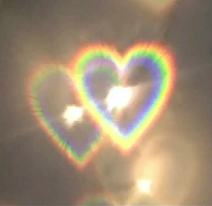 two heart shaped clouds in the sky with rainbow light coming from them and sun shining through