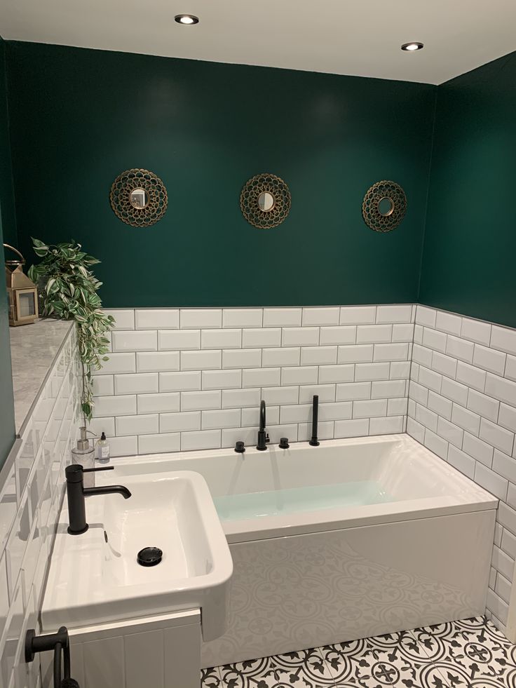 a bath tub sitting next to a white sink in a room with green walls and flooring