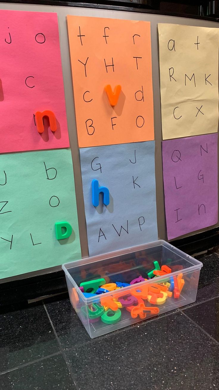 a plastic container filled with letters and numbers sitting on top of a floor next to a wall