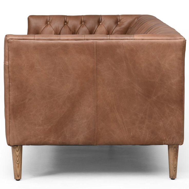 a brown leather couch sitting on top of a wooden frame