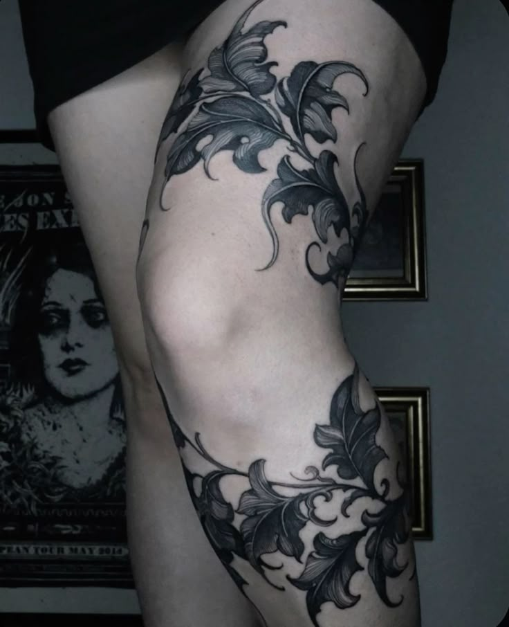 a woman's leg with tattoos on it and flowers in the lower part of her thigh