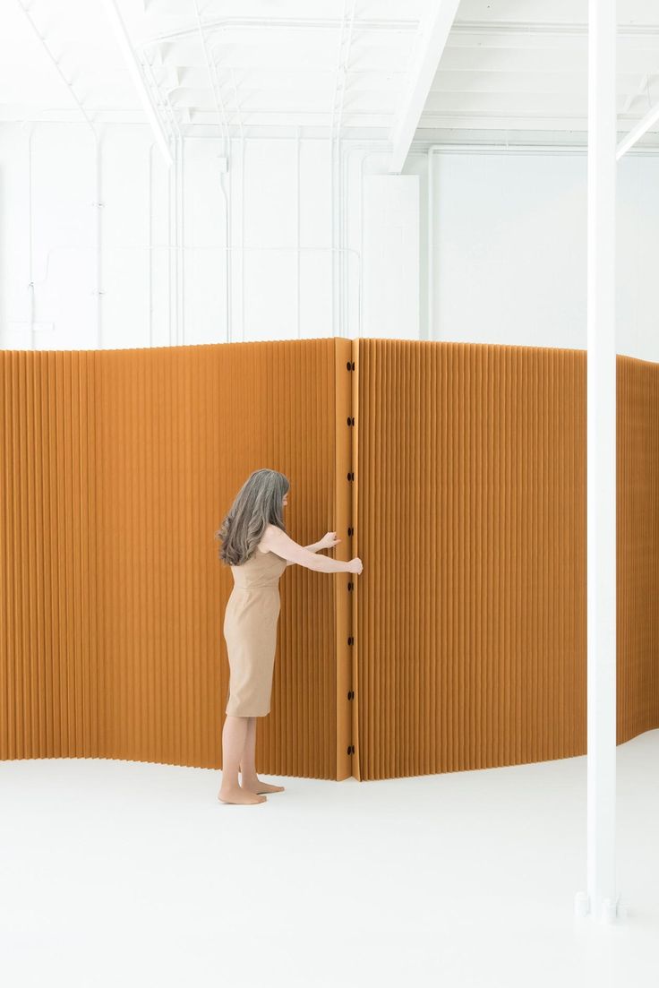 a woman is standing in front of a wall and touching it with her hand,