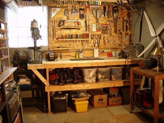 a workbench with many tools hanging on the wall and shelves full of tools