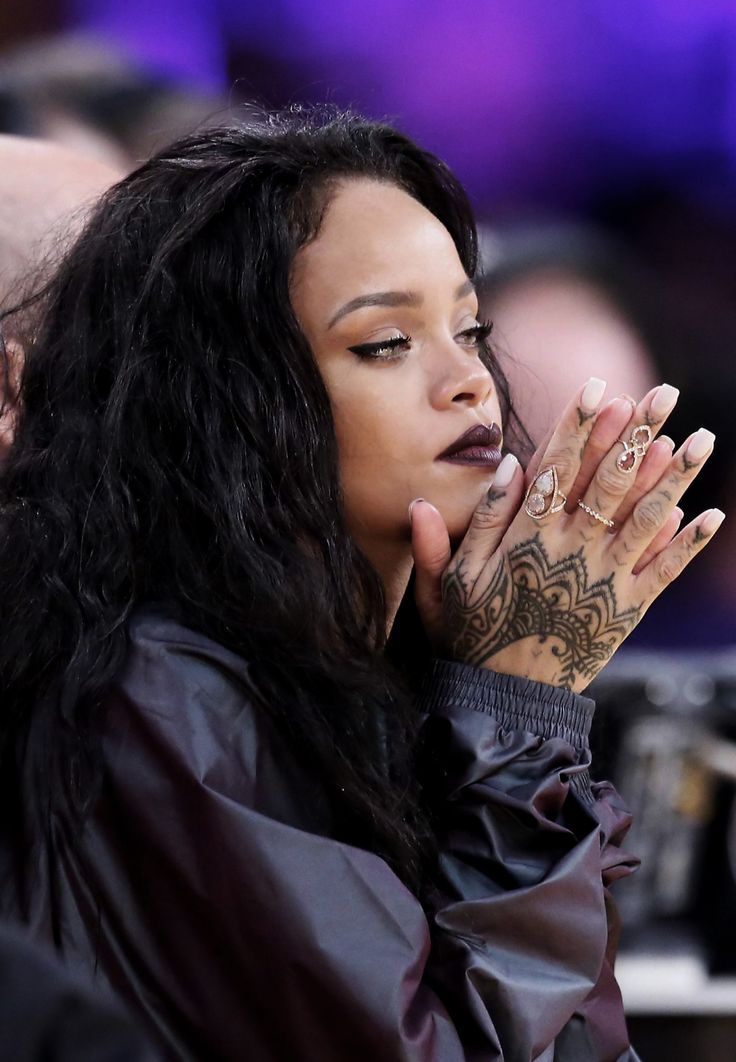 a close up of a person with tattoos on her hand and hands in the air