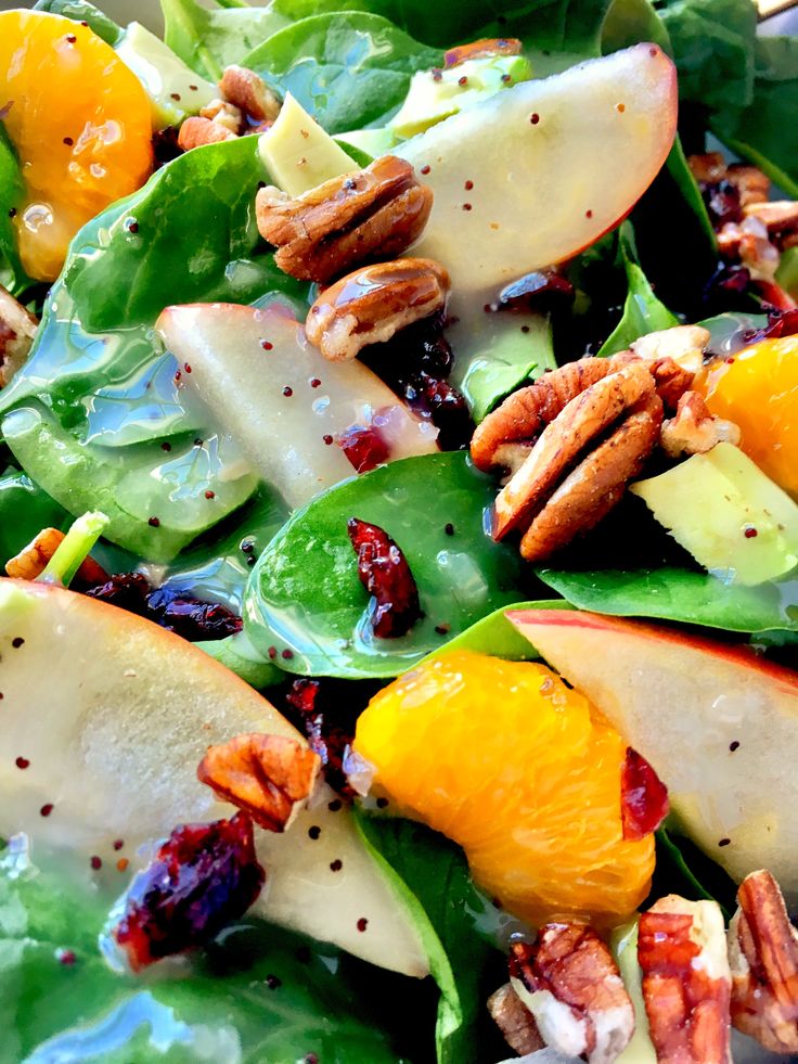 a salad with apples, oranges and pecans in it