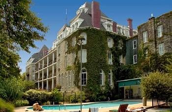 an outdoor swimming pool in front of a large building with ivy growing on it's side