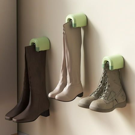 four pairs of boots are hanging on the wall next to each other, with green hooks