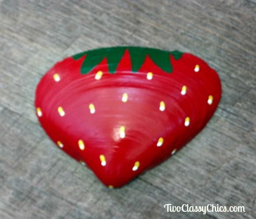 a red strawberry shaped bowl sitting on top of a wooden floor next to a wall