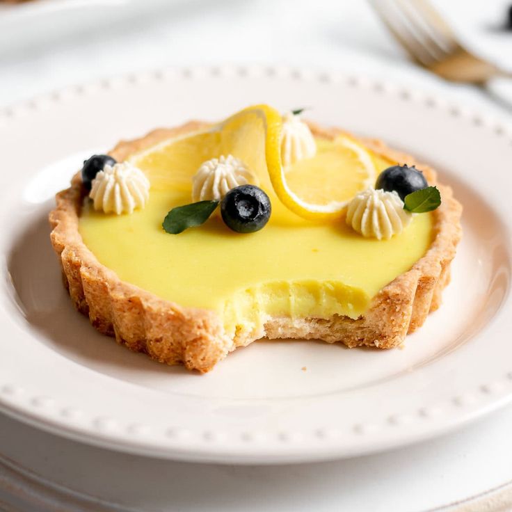 a piece of cheesecake with blueberries and lemons on it is sitting on a white plate