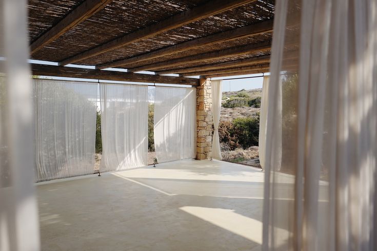 an empty room with sheer curtains on the ceiling