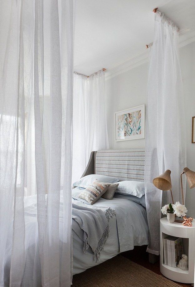 a white bedroom with sheer curtains and a bed