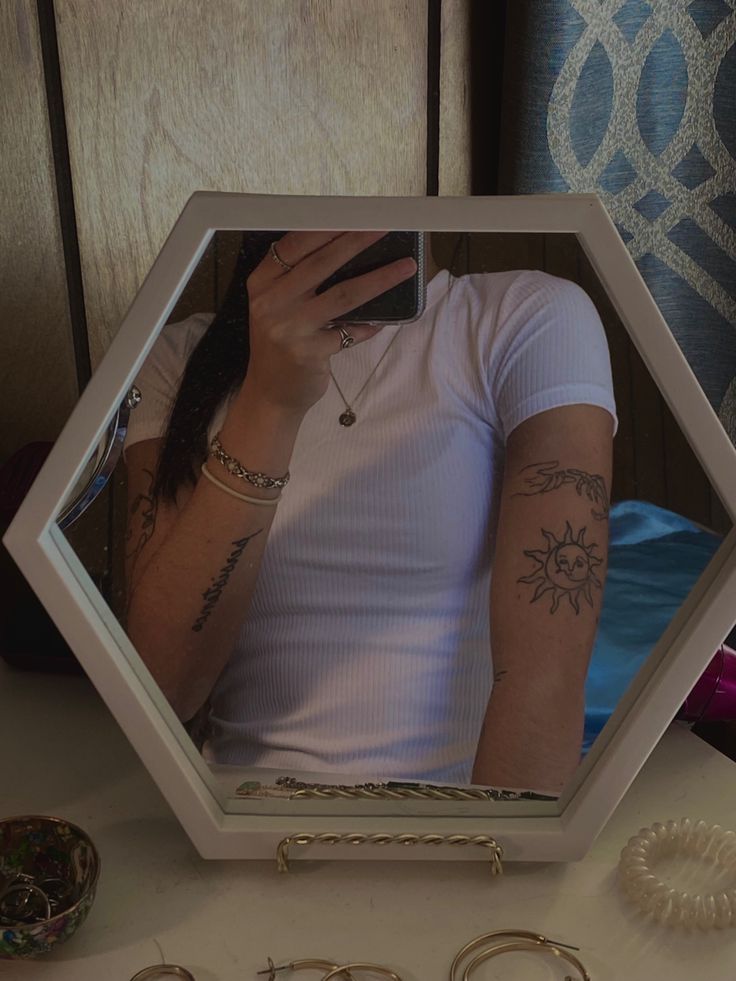 a woman taking a selfie in a mirror with her cell phone and jewelry on the table