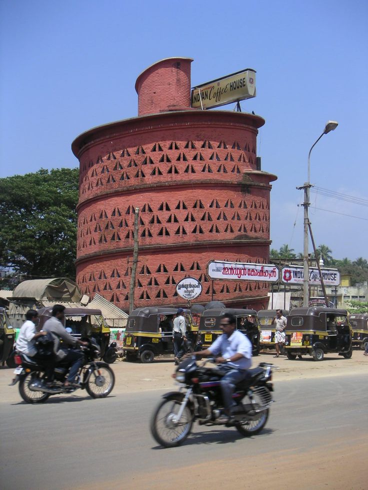 two men riding motorcycles past a tall red building