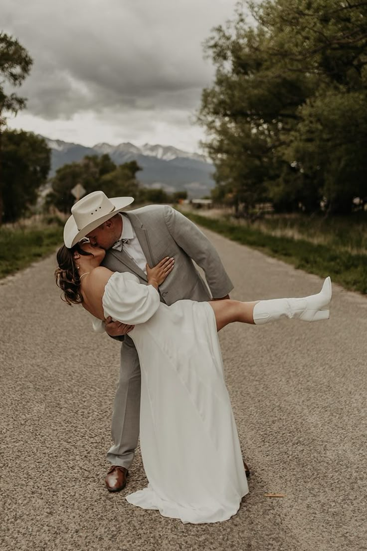 a bride and groom are dancing on the road