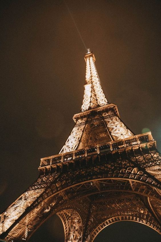 the eiffel tower lit up at night with lights on it's sides