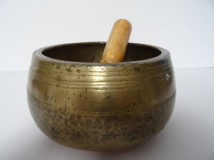 an old metal singing bowl with a wooden stick sticking out of it's side