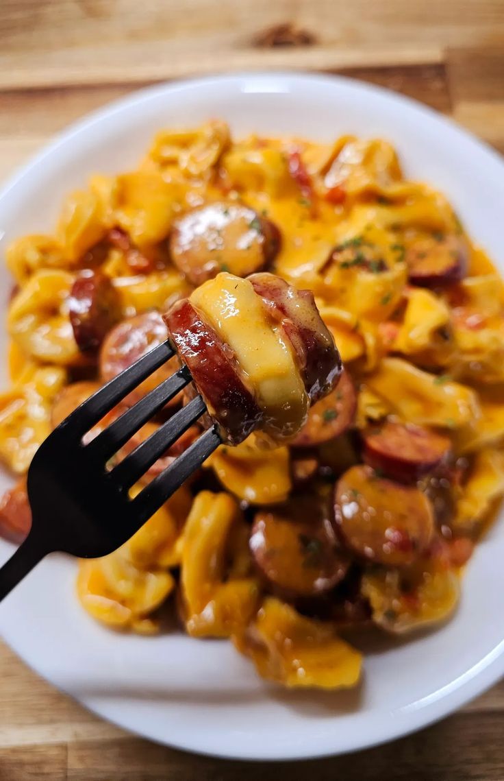 a white plate topped with pasta covered in cheese and bacon next to a black fork