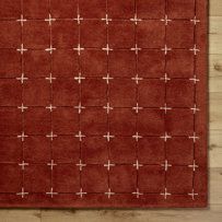 a red rug with white crosses on it in front of a wooden wall and floor