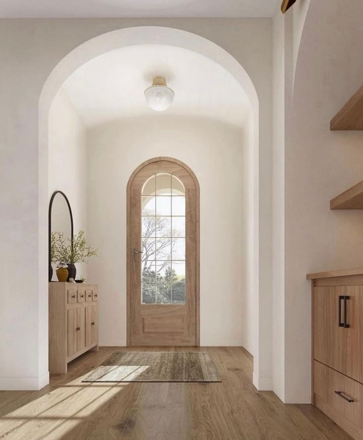 an arched entryway leading to a hallway with wood floors and white walls, along with wooden cabinetry