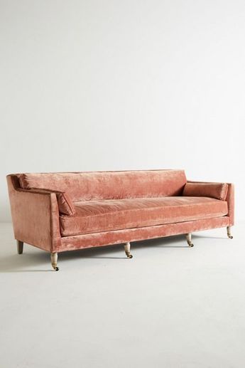 a pink velvet couch sitting on top of a white floor