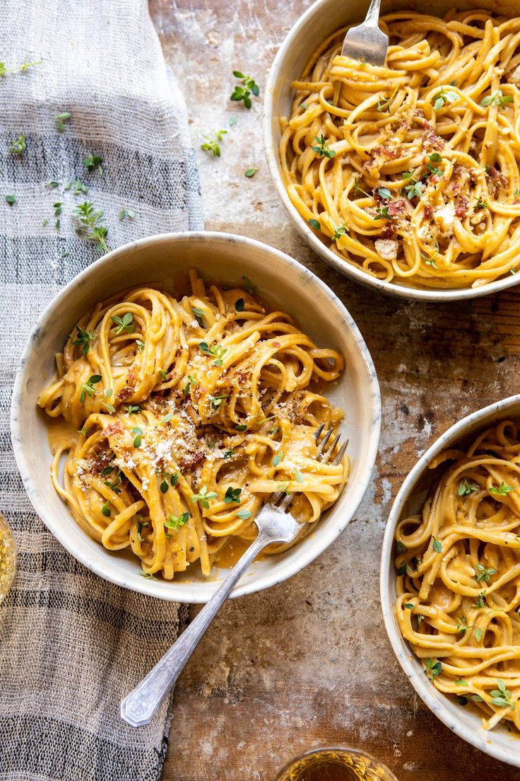 three bowls filled with pasta on top of a table