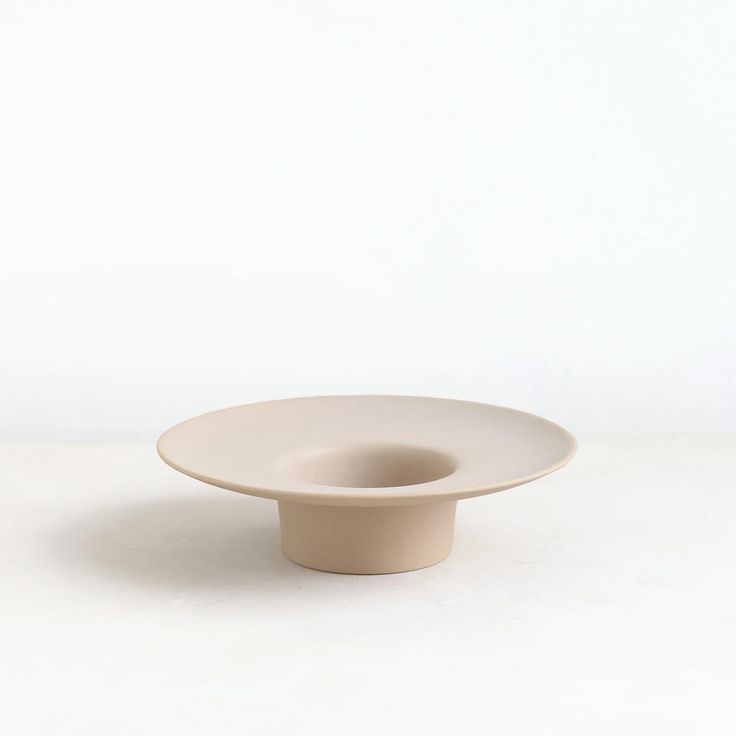 a white bowl sitting on top of a table next to a black object in the middle