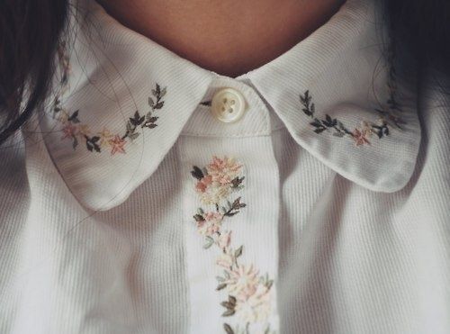 a close up of a woman's shirt with flowers and leaves on the collar