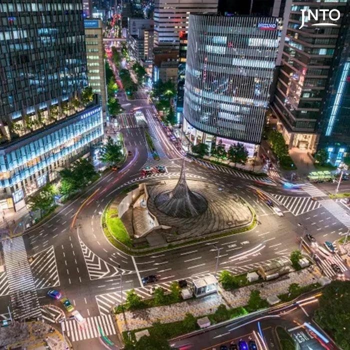 an aerial view of a city at night with traffic and buildings in the foreground