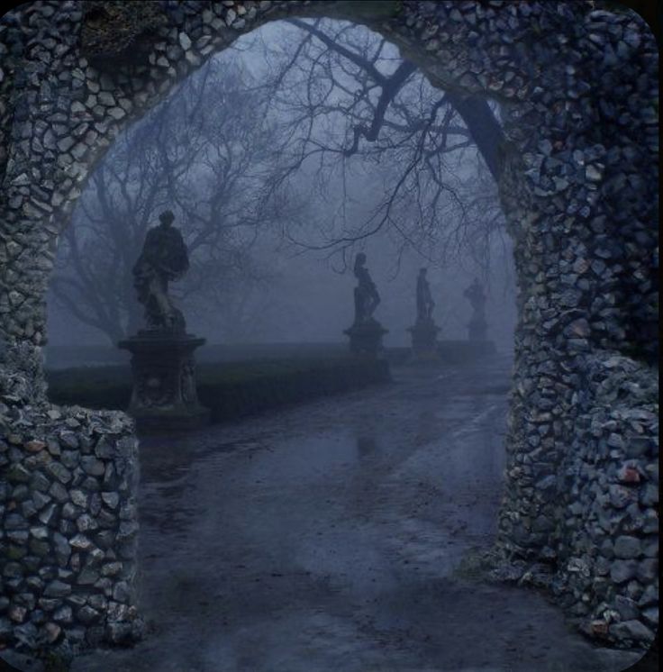 an archway with statues in the middle of it and foggy sky behind them at night