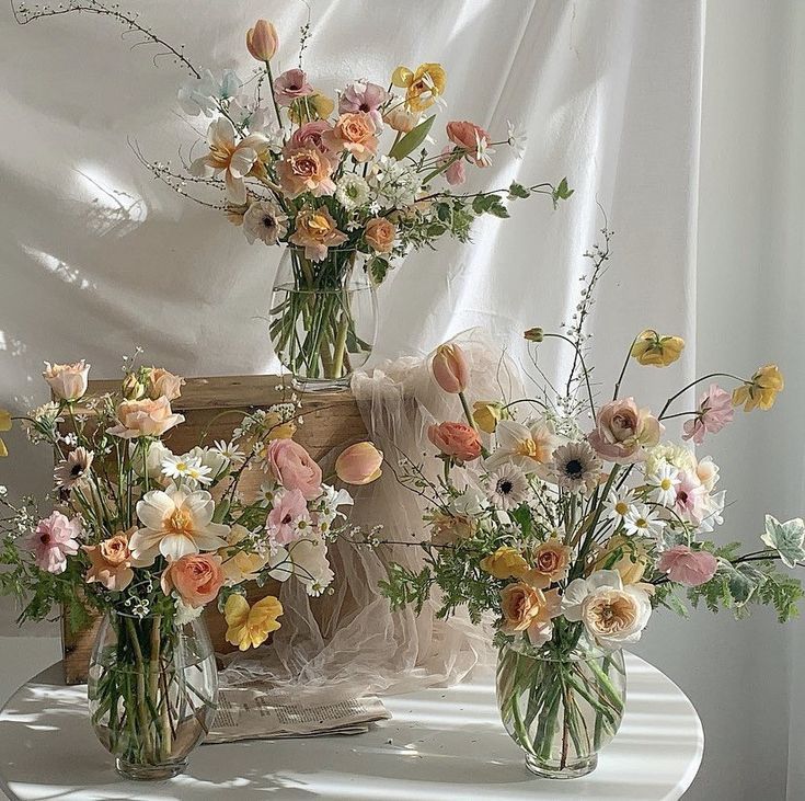 three vases filled with flowers on top of a table