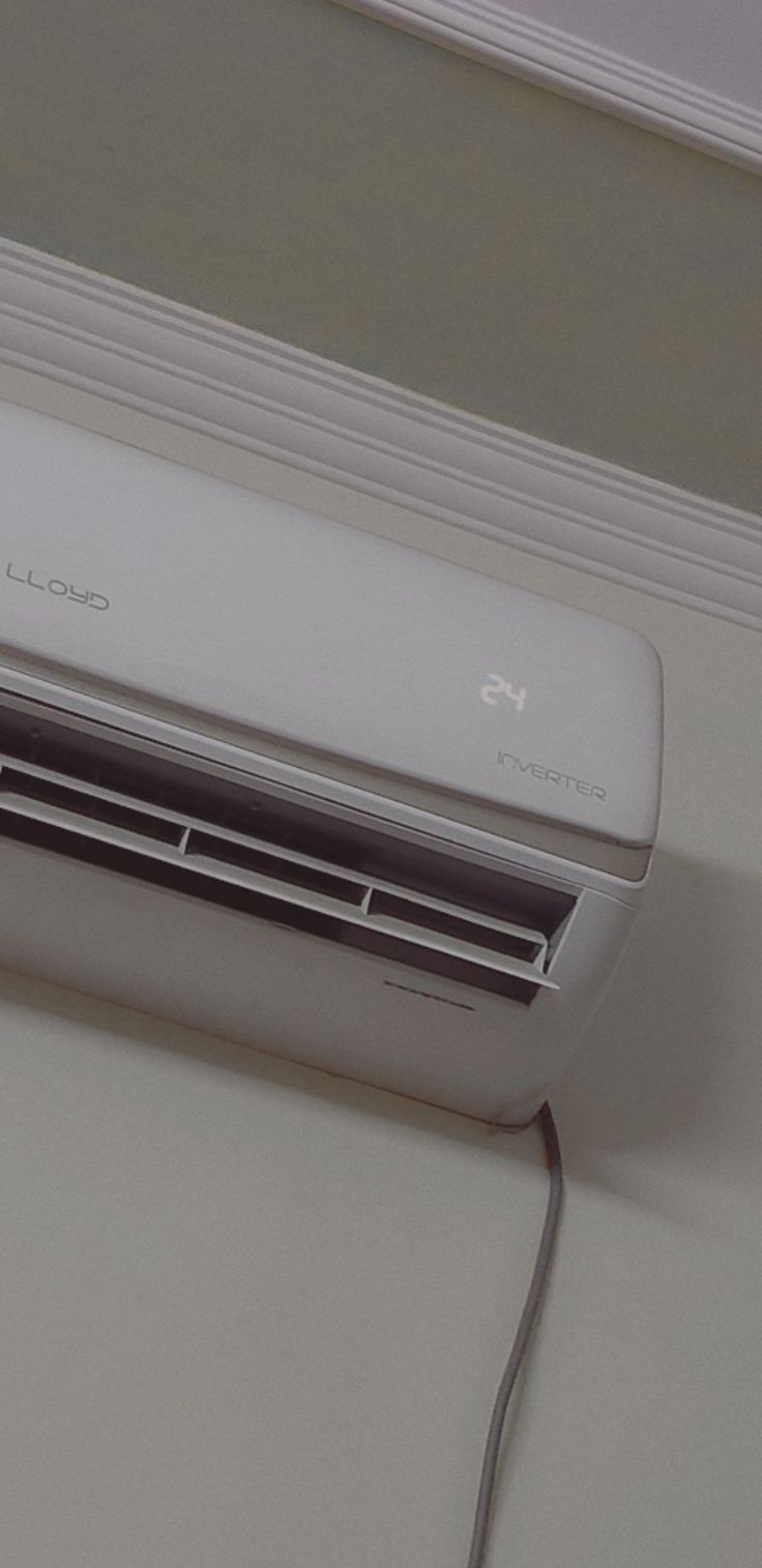 a white air conditioner sitting on top of a counter next to a window sill